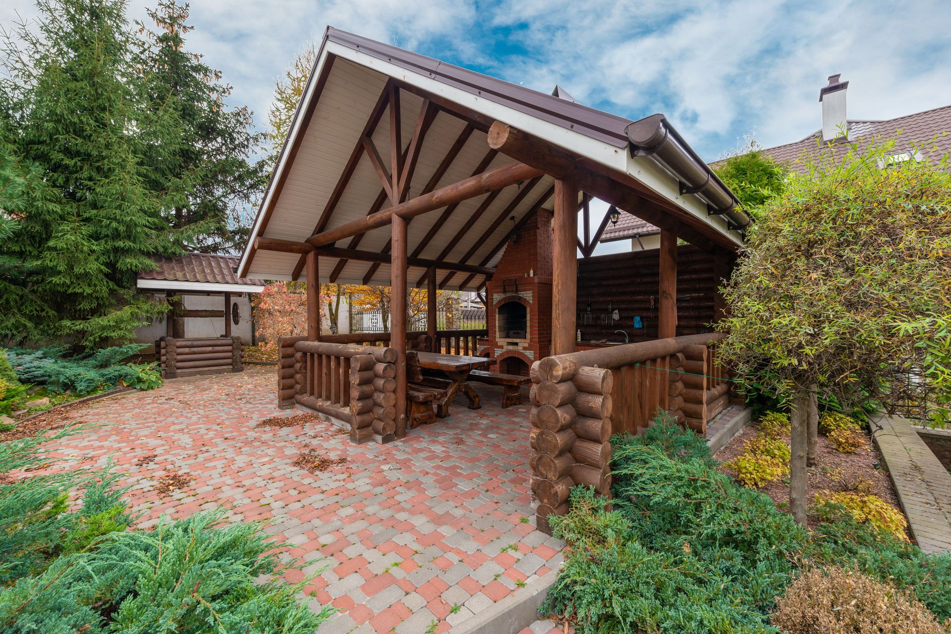 Rustic log pavilion in a garden setting, perfect for outdoor gatherings.